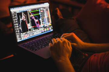 Portrait of attractive nerdy man is working late night on the computer in living room in home office