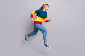 Full length body size photo of blonde girl jumping high running fast in casual clothes isolated on pastel grey color background