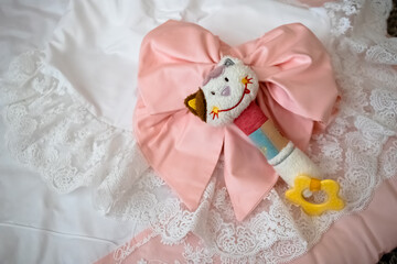 Fototapeta na wymiar a toy next to a pink bow and a blanket with white lace. the concept of motherhood, joy and a luxury lifestyle without people in the