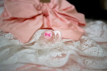 pink baby girl pacifier on white lace baby blanket bow knot close-up side view luxury lifestyle and maternity concept