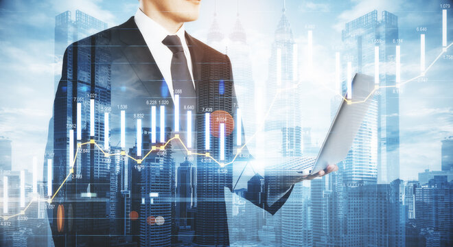 Business analytics concept with businessman following the process by laptop at city background and digital screen with infographic column diagram. Double exposure.