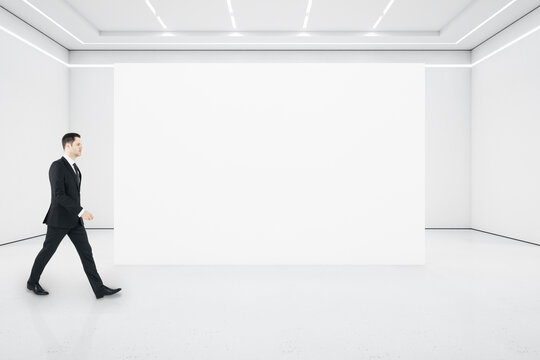 Businessman walking in minimalistic gallery interior