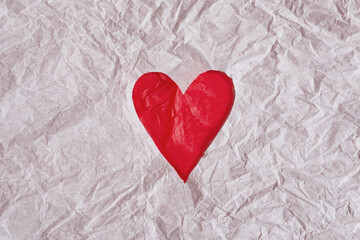 White crumpled paper cut and red heart underneath. White crumpled paper texture background.