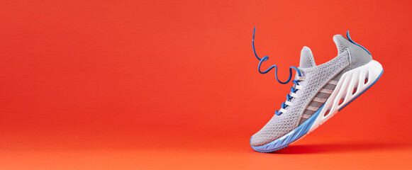 Fashion stylish sneakers with flying laces. Running sports shoes on orange background. - obrazy, fototapety, plakaty
