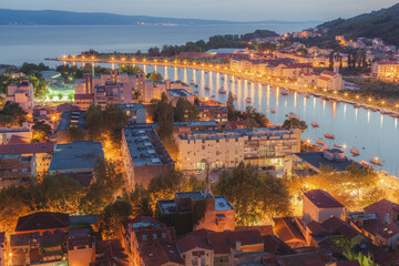 Obraz premium Cityscape view at night over old town Omis and the Cetina River on the Adriatic coast in the Split Dalmatia region of Croatia