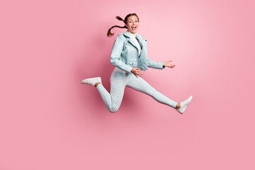 Full length photo portrait of excited girl playing imaginary guitar jumping up isolated on pastel...