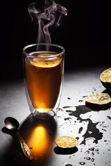 Cup of tea with lemon and visible steam in backlighting