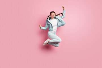 Full length photo portrait of cheerful girl celebrating jumping up isolated on pastel pink colored background
