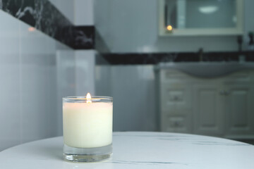 aromatic scented candle glass is put on the white marble table in a luxury white bathroom toilet to creat relax and cozy and clean ambient