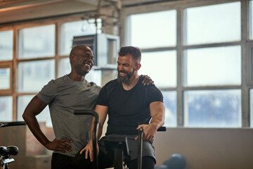 Two men laughing after a stationary bike exercise session