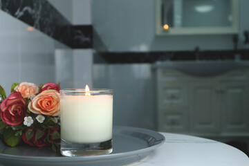 aromatic scented candle glass is put on the white marble table in a luxury white bathroom toilet to creat relax and cozy and clean ambient