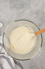 Dough for making a vanilla cake with blueberries in a bowl on a gray concrete background. Recipe step by step. Top view.