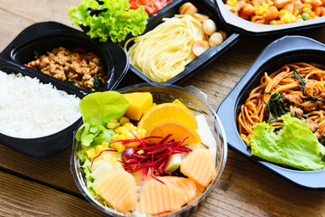 Service food order online delivery Spaghetti italian pasta macaroni cheese with sausage rice and fruit on food box, Food delivery in take away boxes package on wooden table at home.