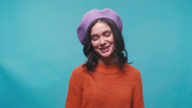 happy young woman in beret smiling isolated on blue