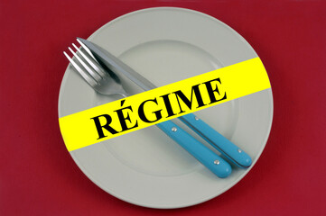 Assiette sur fond rouge avec des couverts et un bandeau sur lequel est écrit régime