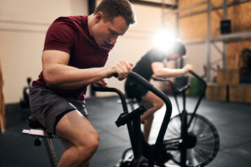 Fototapeta na wymiar Two young men exercising on stationary bikes at the gym