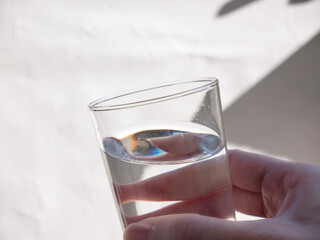 水が入った透明グラスを持つ手。水分補給、水を飲む。