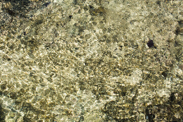 Abstract of the shallow water with light scatter from the pebbles in the crystal clear water. Makes an excellent computer screen background.