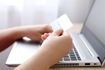 Woman holding credit card types on laptop keyboard. Concept of online shopping and payment, financial transactions
