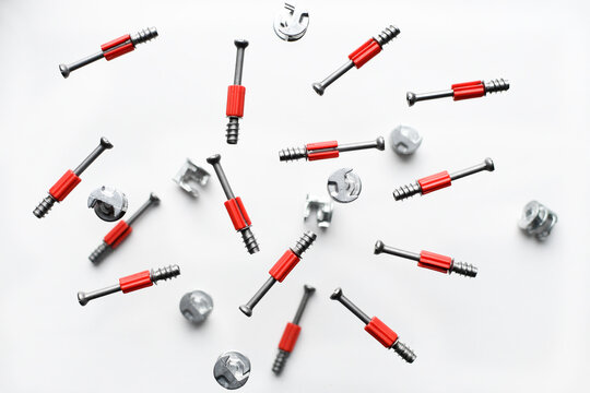 Minifix bolt set, with plastic shaft, eccentric. Background from screws and dowels. Collection of metal bolts on a white background. Levitation of objects on white background