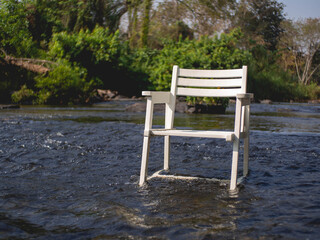 Fototapeta premium White wooden chair in the middle of the river at coffee shop called 