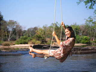 Woman on a wooden swing and a river