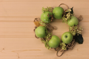 A wreath of green apples and hydrangea flowers on a wooden background. Fall. Harvest.