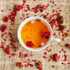 View from above of a cup of herbal tea, with the herbs scattered around