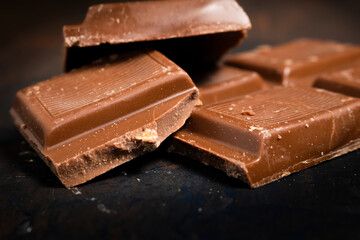 Tablet pieces of dark chocolate on a dark surface.