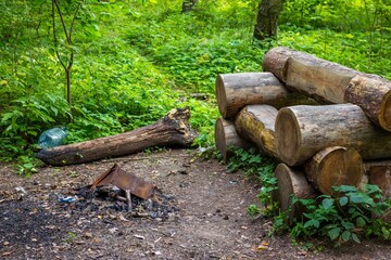 A wooden bench made of logs and a fireplace in nature. Rest place in the park