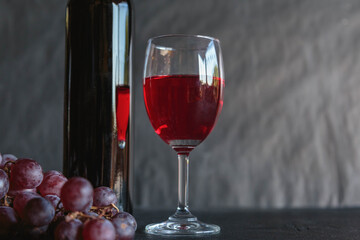 Red wine and wine bottle with grapes on black background