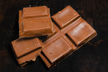 Tablet pieces of dark chocolate on a dark surface.