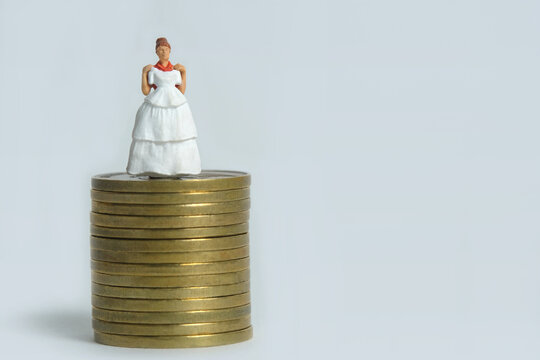 Wedding dress budget for bride, miniature people illustration concept. Woman standing above coin money stack. Image photo - Powered by Adobe
