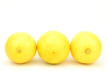Three lemons, laid out in a row and isolated on a white background.