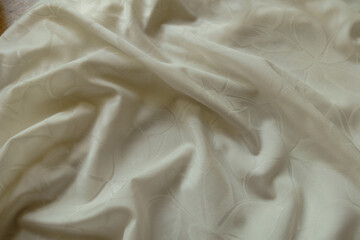 Folded glossy cream colored polyamide fabric with floral pattern