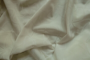 Glossy cream colored polyamide fabric with floral pattern in soft folds