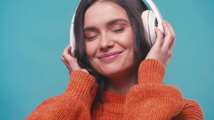 pleased woman in wireless headphones listening music isolated on blue - Powered by Adobe