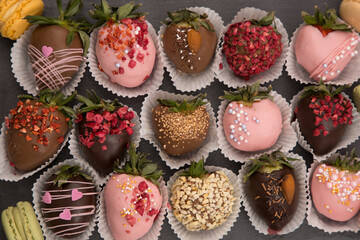 Variety of strawberries covered with chocolate, dark and white chocolate and nuts, on a black background