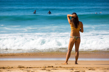 back of a sexy woman in bikini on portugal ocean beach background. copy space