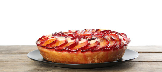 Delicious plum cake on wooden table against white background