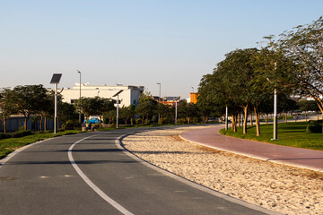 Fototapeta na wymiar Jogging and cycling tracks in Al Warqa park, Dubai, UAE early in the morning. Lamp post powered by solar panels can be seen in the picture.