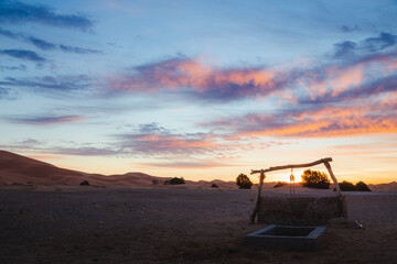 A colourful sunrise or sunset over a water well outside the village of Merzouga, the gateway to the Erg Chebbi desert dunes in Morocco.