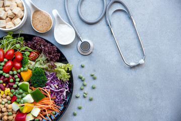 Health Care.  Fresh vegetable salad with medical stethoscope and equipment dumbbell for diet and...