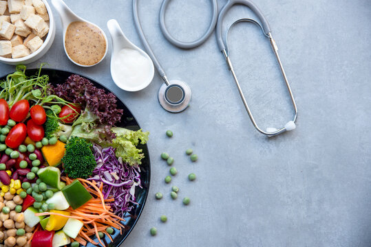 Health Care.  Fresh vegetable salad with medical stethoscope and equipment dumbbell for diet and weight loss for healthy care and protect virus,