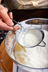 Sifting flour through a sieve. Dough preparation process. Workflow in a bakery. Rustic style.