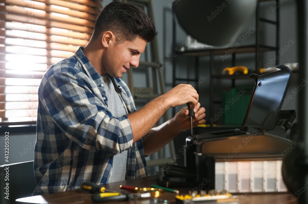 Wall mural Repairman with screwdriver fixing modern printer in office