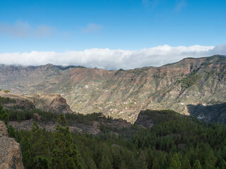 Fototapeta na wymiar Scenic view of amazing landscape at Roque Nublo park in inland central mountains from famoust Gran Canaria hiking trail with green pine trees and picturesque rock formation. Canary Islands, Spain.