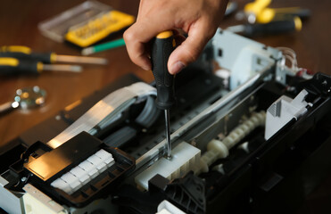 Repairman with screwdriver fixing modern printer, closeup