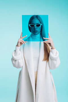 High fashion shot of model wearing casual coat and holding a square blue filter 