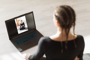 A woman is doing online yoga at home with a trainer. Concept on the topic of remote training